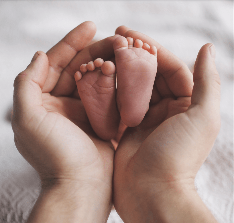 closeup of hands cupping baby's feet